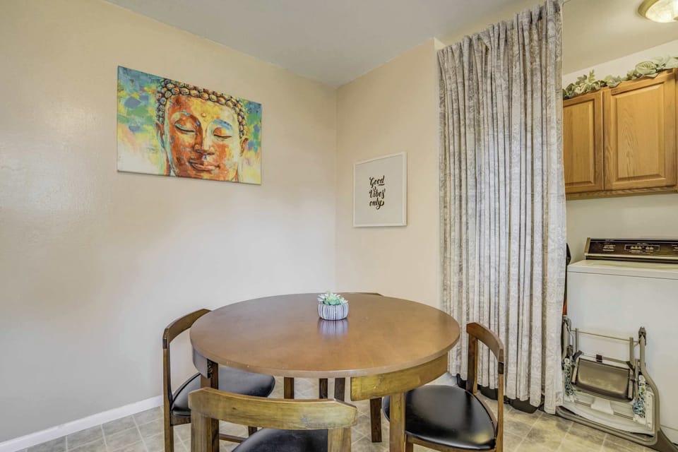Cozy dining nook with seating for four, colorful wall art, and convenient access to the laundry area tucked just behind the curtain.

