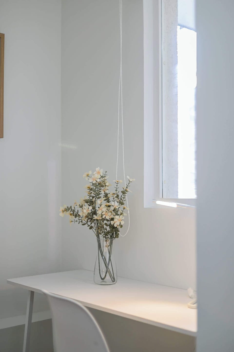 A serene workspace featuring a minimalist desk and a touch of nature with fresh flowers, perfect for relaxation or productivity.