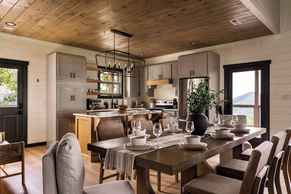 Modern kitchen and dining area with mountain views and a wooden ceiling.