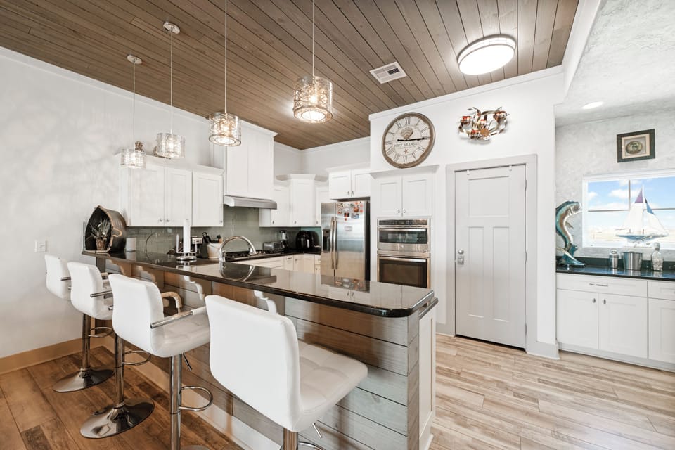 Gather around your stunning granite island where crystal chandeliers cast warm light across sleek surfaces, perfect for morning coffee or evening conversations.