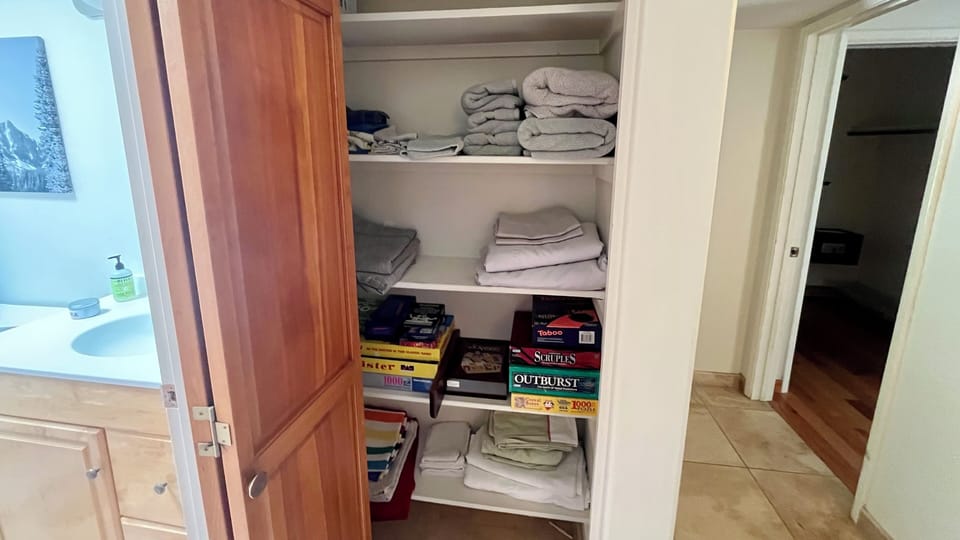 Linen closet with extra sheets and towels along with games on games on games