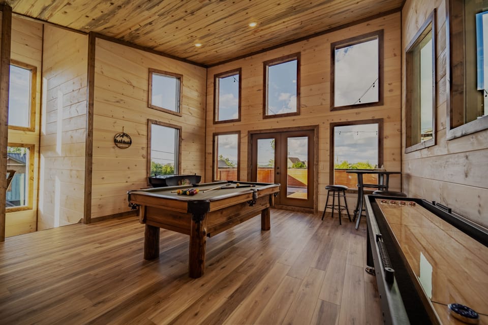 Game room w/ sleeper sofa, 70 inch smart TV, pool table, shuffleboard, & arcade.