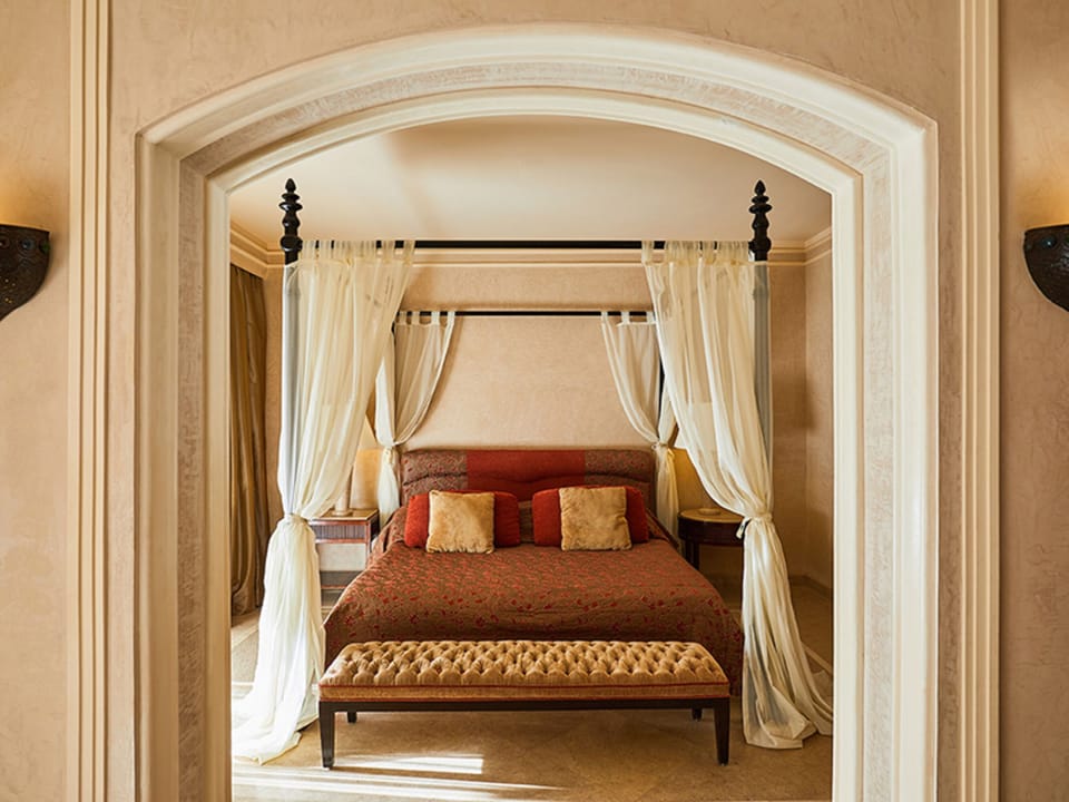 Drift off in a plush canopy bed with warm, golden light.