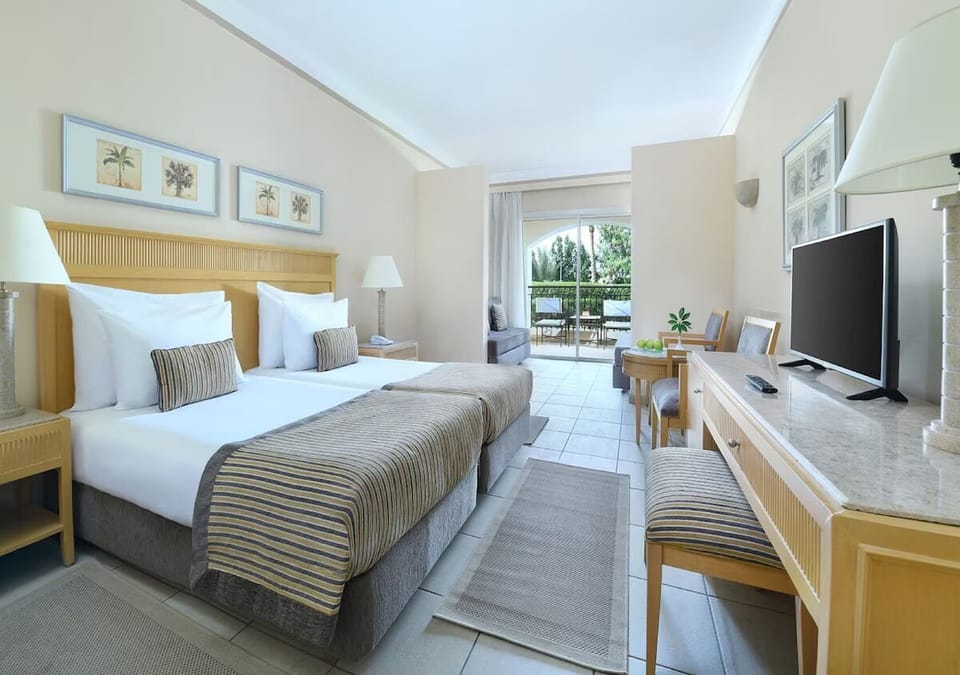 Settle into a bright bedroom with desk, TV, and balcony.
