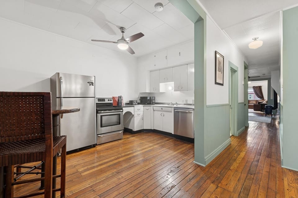 Cook your favorite meals in this fully equipped kitchen with stainless steel appliances, white cabinetry, and warm hardwood floors throughout.