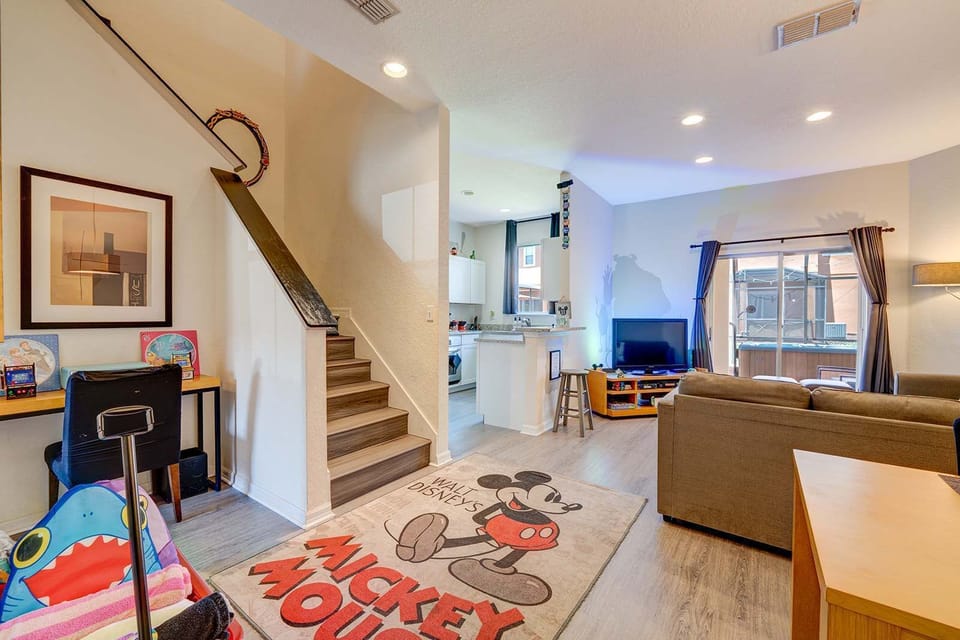 Open living area with a playful mickey mouse rug and natural light from sliding glass doors.