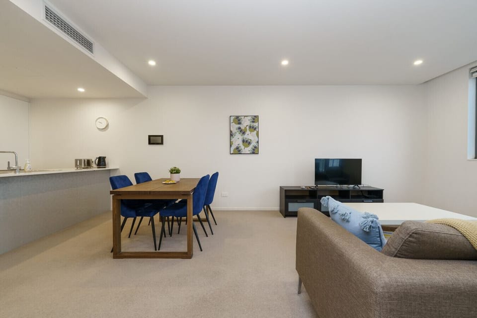 Open-plan living with a cosy lounge, a dedicated dining space for four, and a sleek TV console.