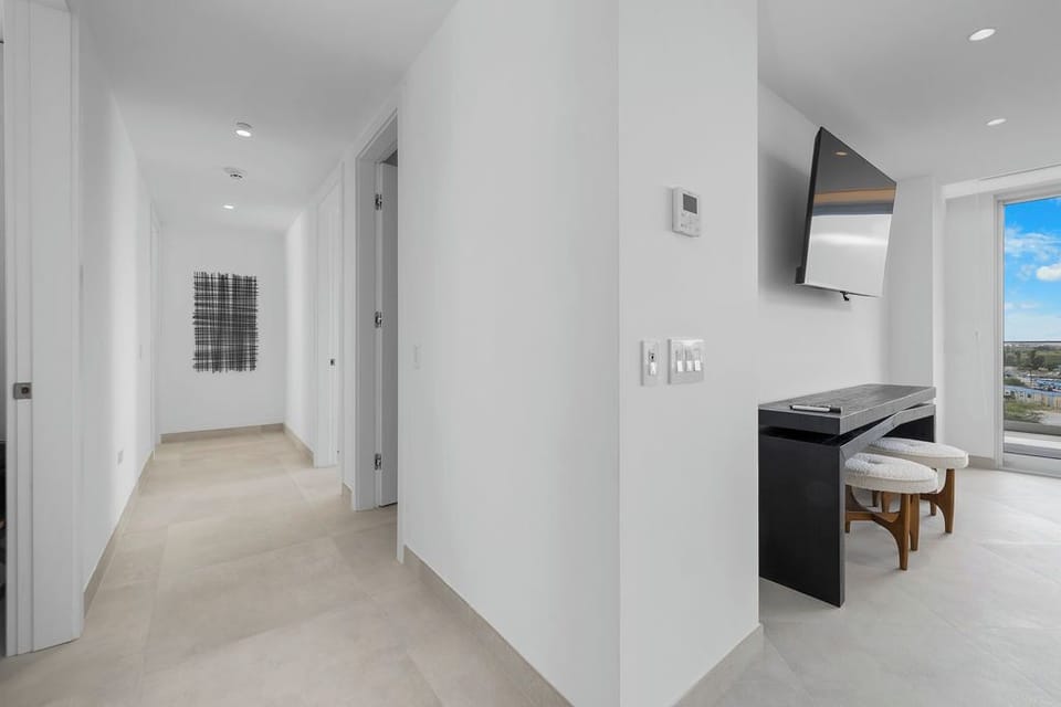 Modern, minimalist hallway flows into a sleek workspace with city views—your bright, open home away from home where comfort meets contemporary style.