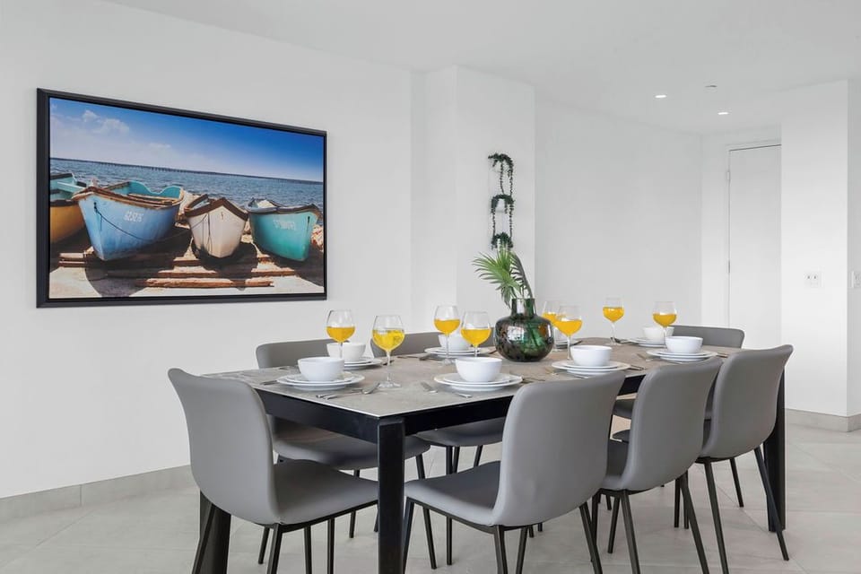 Step into your dining space where gatherings come alive around a sleek table set for eight. A vibrant coastal artwork adds a splash of color, inviting you to share meals and memories together.