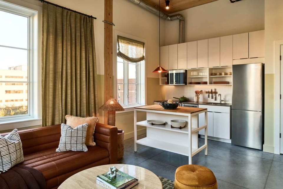 Comfy sofa and kitchen space with large windows and warm light