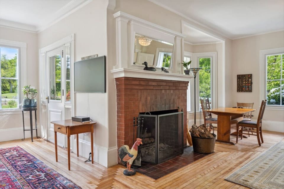 Spacious, bright living room with a Frame Smart TV, fireplace, plenty of seating, a table for cards, and a large bay window.