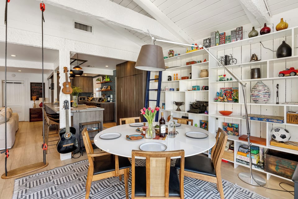 Eclectic and playful dining space featuring a round table, open shelving full of curios, and even a swing.