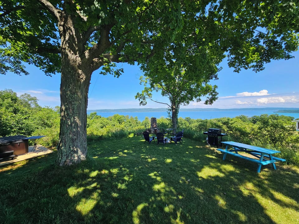 OVERVIEW:  The outdoor hot tub, grill, bonfire ring, and picnic table with Crystal Lake in the background.