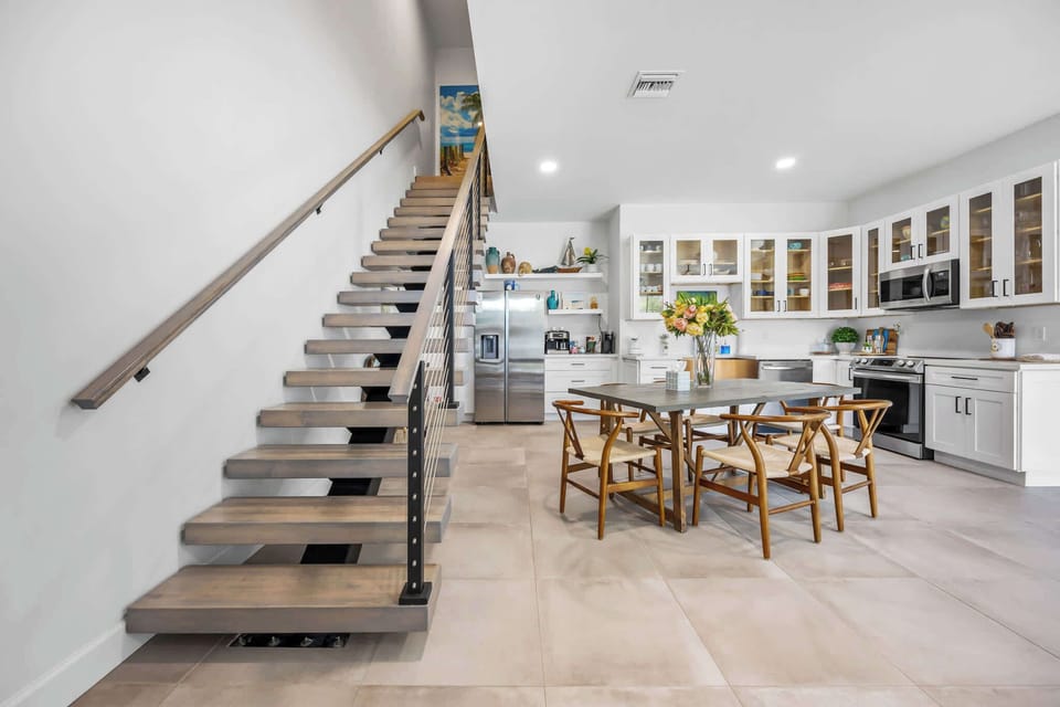 Modern kitchen and dining area with open shelving and a floating staircase.