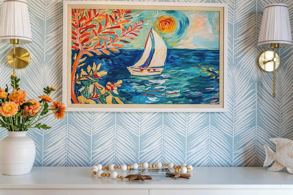 Vibrant coastal artwork and chic lighting create a cheerful focal point in this beach-inspired space. Bright colors, nautical charm, and elegant details bring warmth and personality to the room’s relaxing seaside vibe.