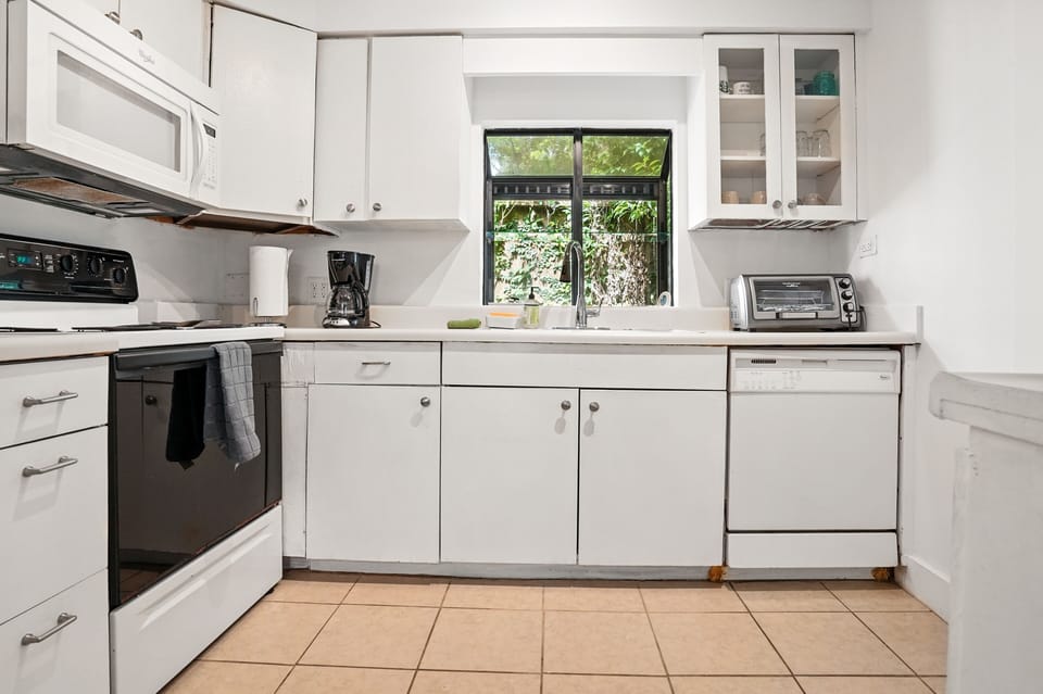 Kitchen Third Angle - Large window over the sink, white cabinets, and tiled floor complete the kitchen view.