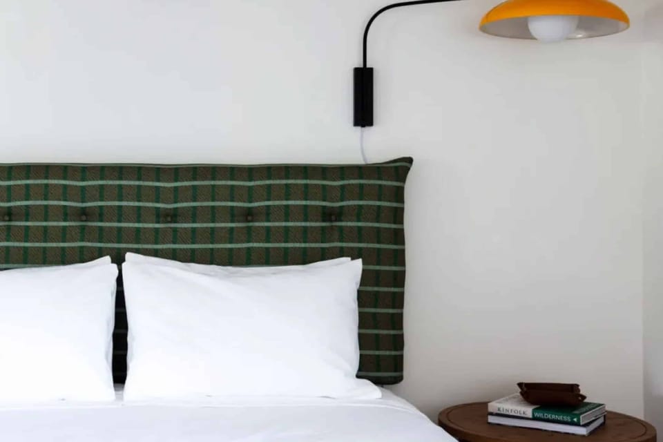 Sink into plush pillows beneath warm, designer bedside lighting.