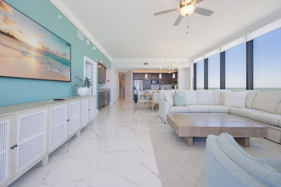 Unwind in the spacious living area featuring a large sectional sofa with queen sleeper and panoramic beachfront scenes