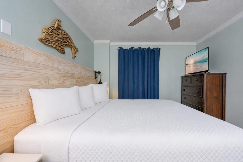 Cozy master bedroom featuring a king bed, elegant wooden furnishings, and a wall-mounted TV for relaxation and entertainment