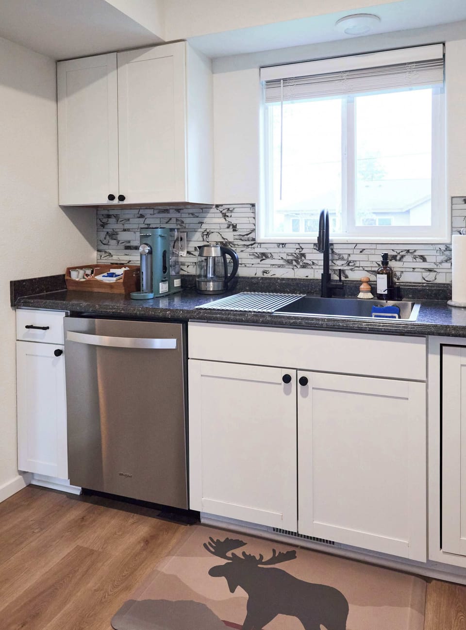 Enjoy a bright kitchen with stainless steel appliances, modern backsplash, and a playful moose rug. A fully stocked coffee and tea station ensures the perfect start to your day, while natural light makes this space warm and inviting.