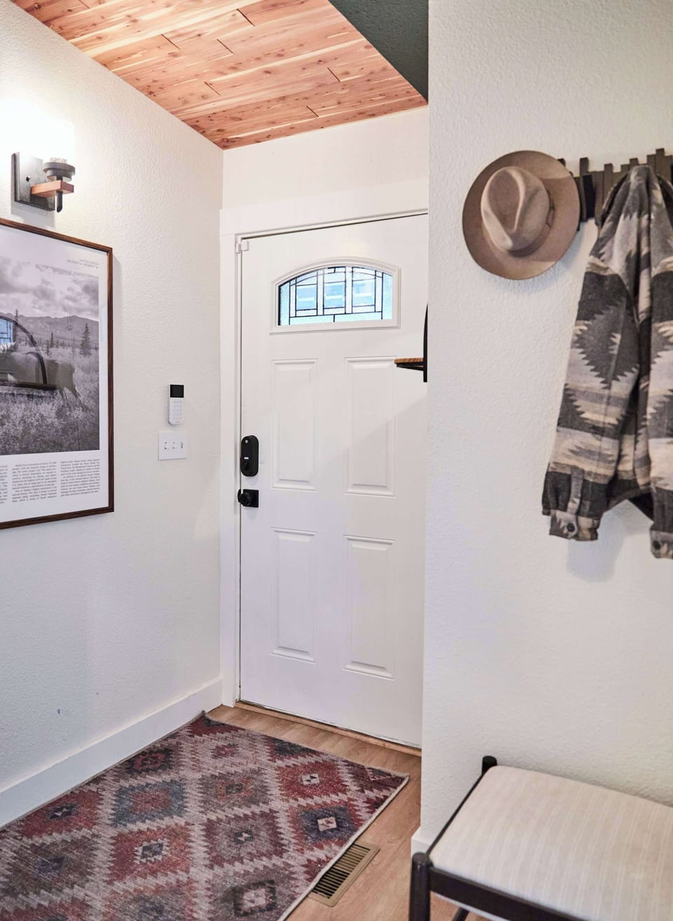 Welcome home through a bright entryway with rustic charm. A patterned rug, coat hooks, and bench offer convenience, while warm Cedar accents and wall art create a stylish first impression as you step inside.
