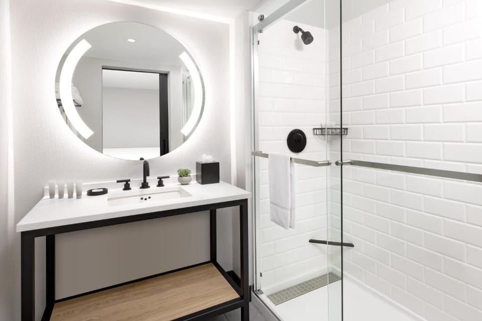 Refresh under a sleek glass shower with glowing vanity mirror.