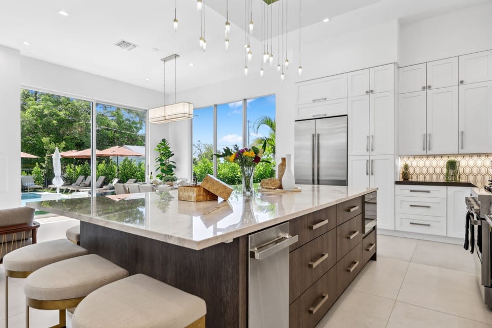 Bright and modern chef’s kitchen with marble island and pool views—your Delray Beach stay, elevated.