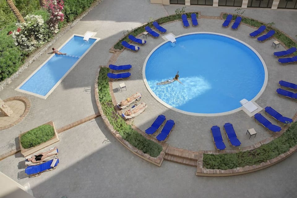 Soak up sunshine as swimmers glide through sparkling blue water.