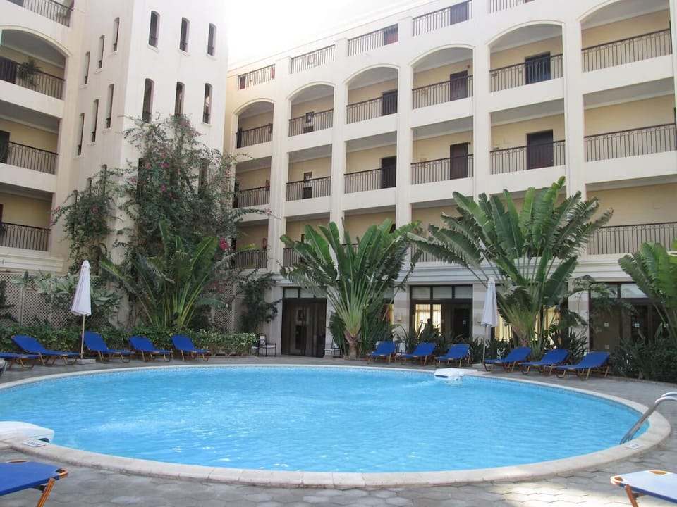 Unwind poolside beneath palms in a serene courtyard oasis.