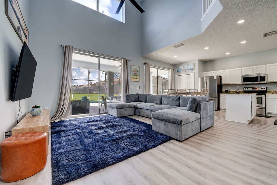 Open living area w/ soaring ceilings & bold blue rug.
