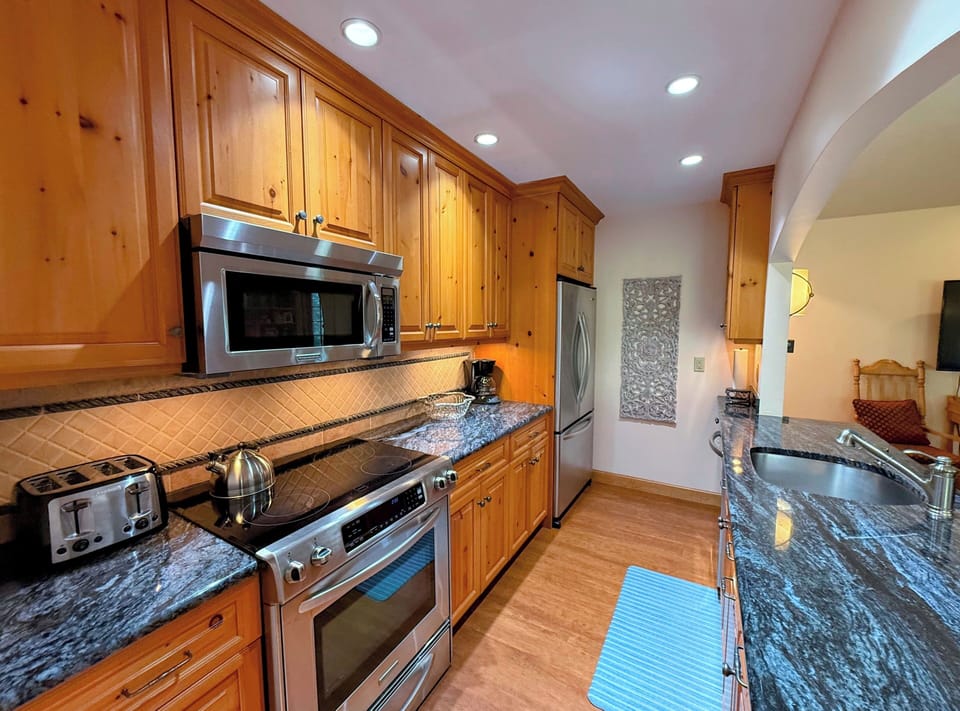 Modern, fully equipped kitchen with granite countertops, stainless steel appliances, and custom cabinetry