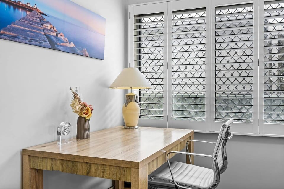 Nestled beside the lounge, a quiet desk nook invites you to read, write, or work remotely, bathed in soft natural light filtering through plantation shutters.