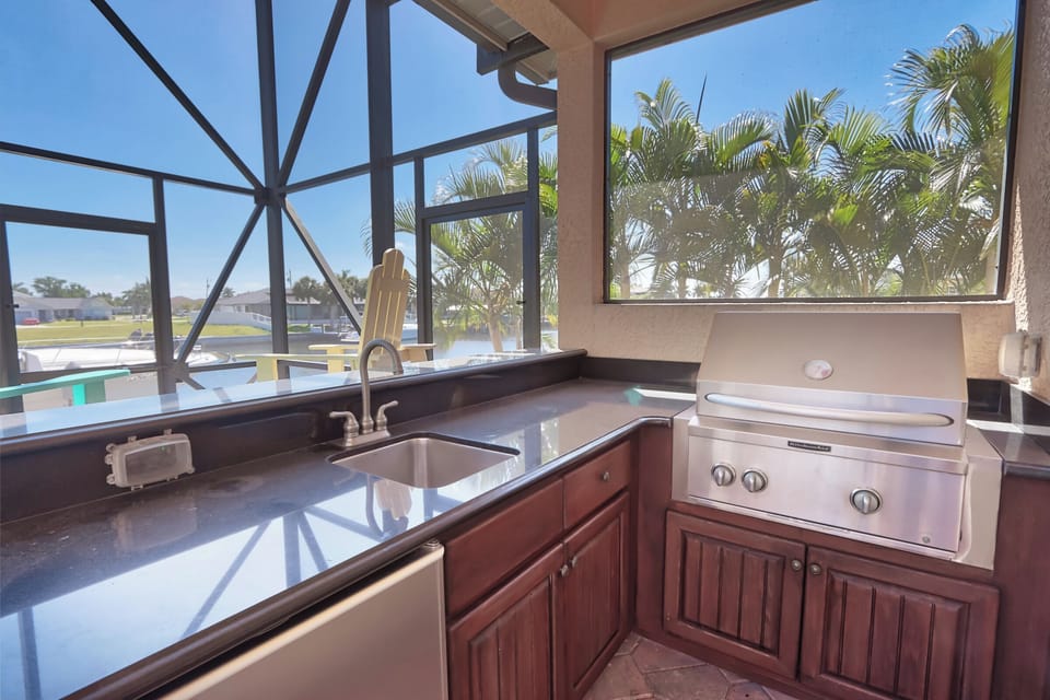 This outdoor space features a wet bar, BBQ grill, and mini fridge — perfect for serving drinks and grilling meals poolside