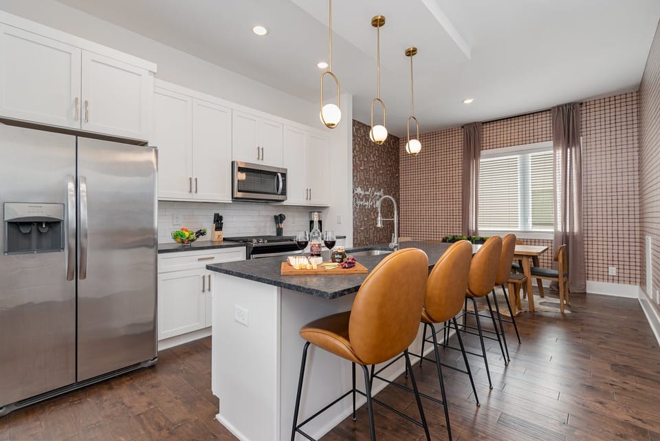 The fully equipped modern kitchen is stocked with all culinary essentials, stainless-steel appliances, breakfast bar seating, and mini bar area with wine cooler.  (2nd Floor)
