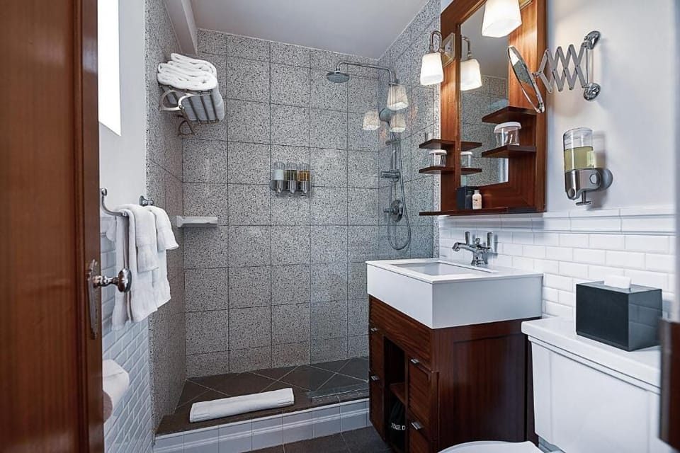 Refresh under a rainfall shower in a sleek tiled bath.