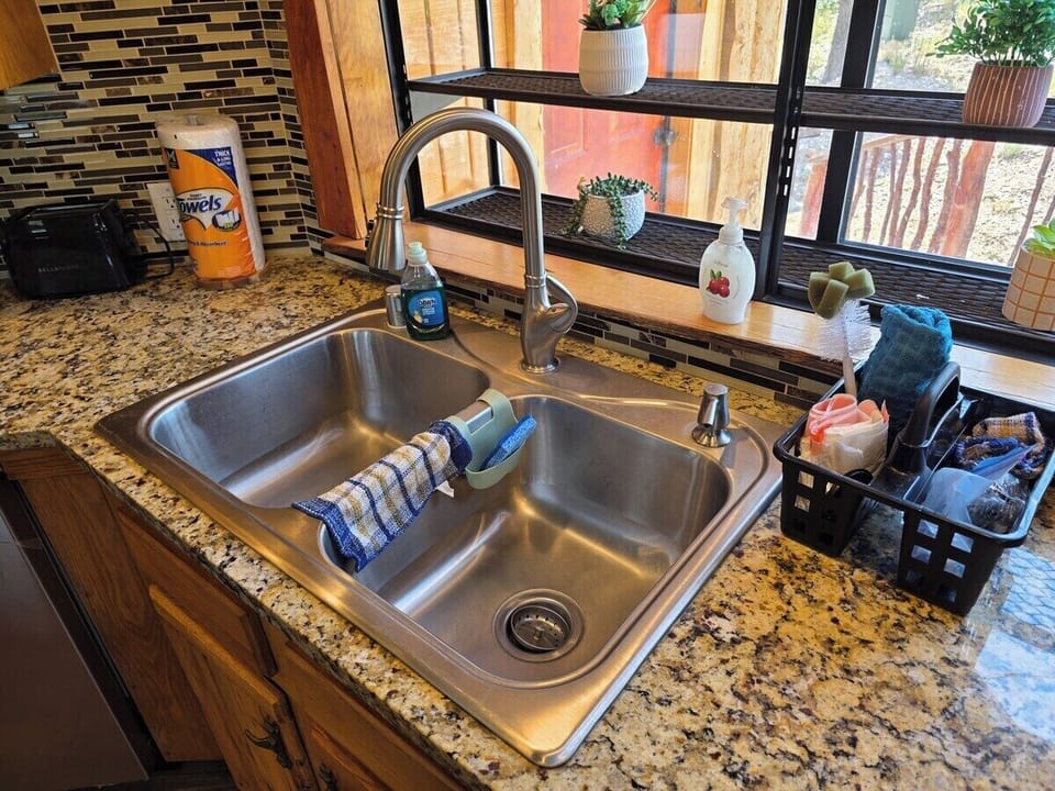 Garden window over the kitchen sink — mountain pines outside and the grill on