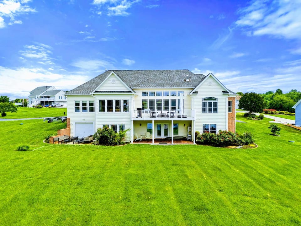 Rear Exterior - The home opens up to the lake with walls of windows, an expansive deck, and a walkout lower level.