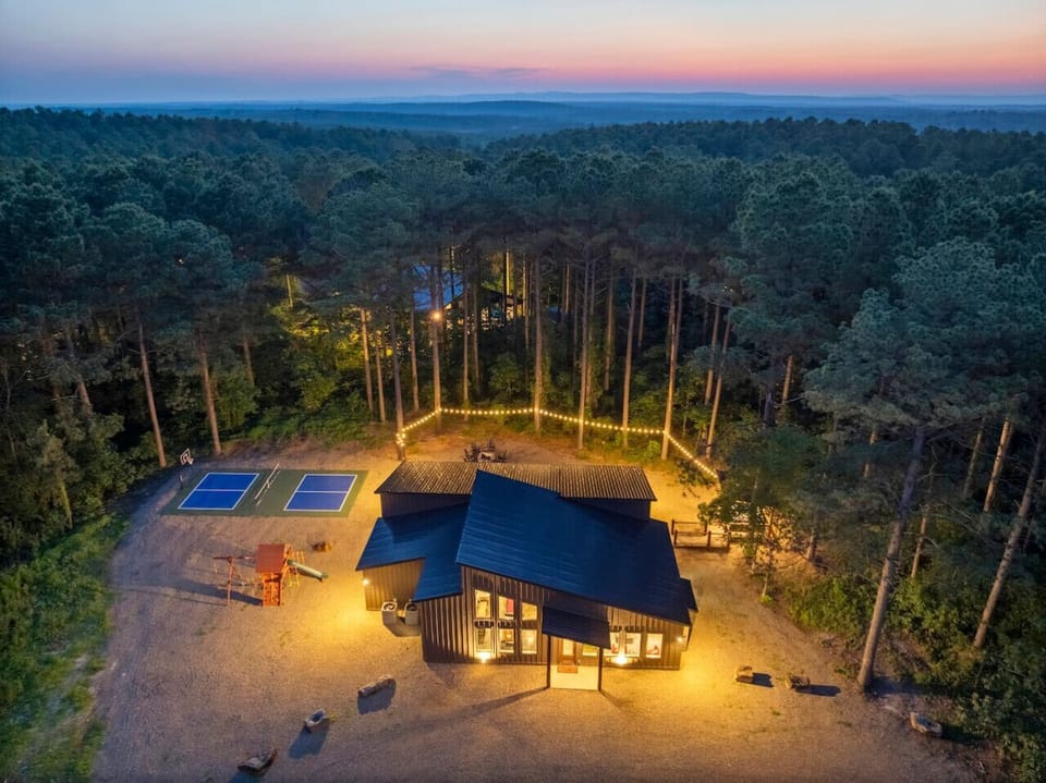Cozy modern cabin nestled in the pines with a sports court, play area, and glowing string-lit fire pit — perfect for a peaceful escape.
