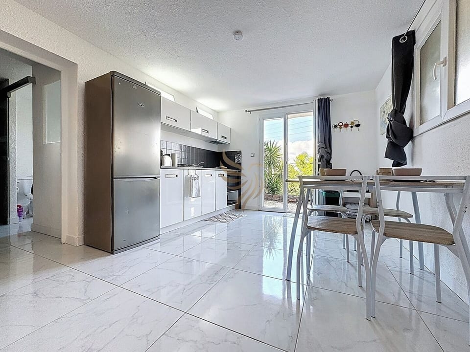 La cuisine moderne s'ouvre sur un coin repas lumineux avec vue sur le jardin. Idéale pour des repas conviviaux, la table peut facilement être déplacée pour plus d'espace.