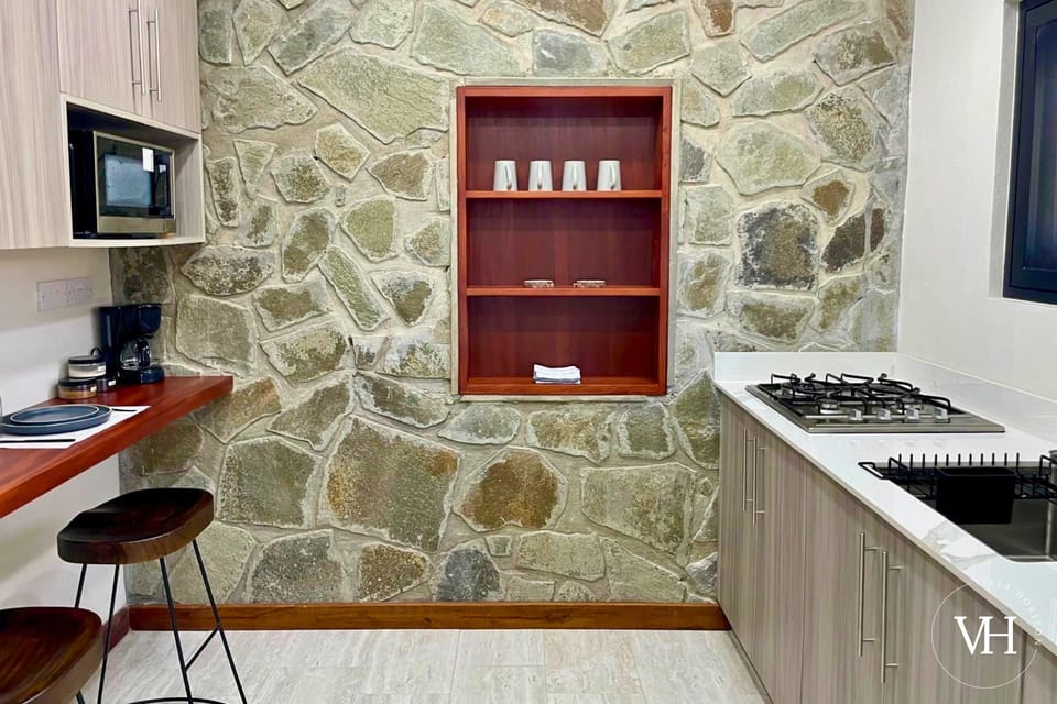Soursop Suite - Full kitchen with fridge, stove, sink, cooking essentials, and a coffee.
