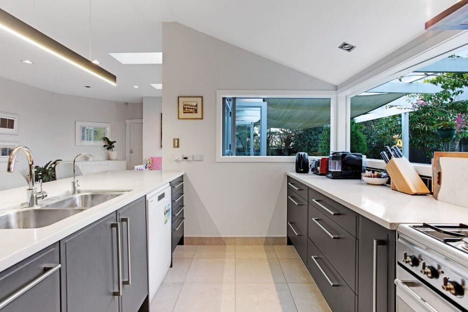 The kitchen is light-filled with large windows and modern appliances.