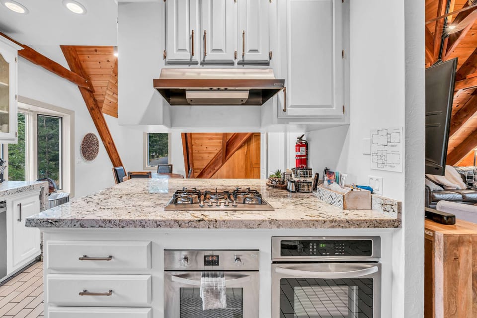 Kitchen: Stainless steel appliances, bar seating, tableware, cookware, gas range 