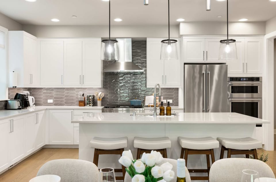 A modern kitchen with white cabinetry, stainless steel appliances, and a spacious island with bar seating. 