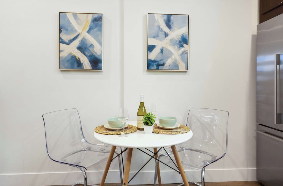 Share meals at this sculptural table with abstract wall art, the transparent chairs keep the space clear.