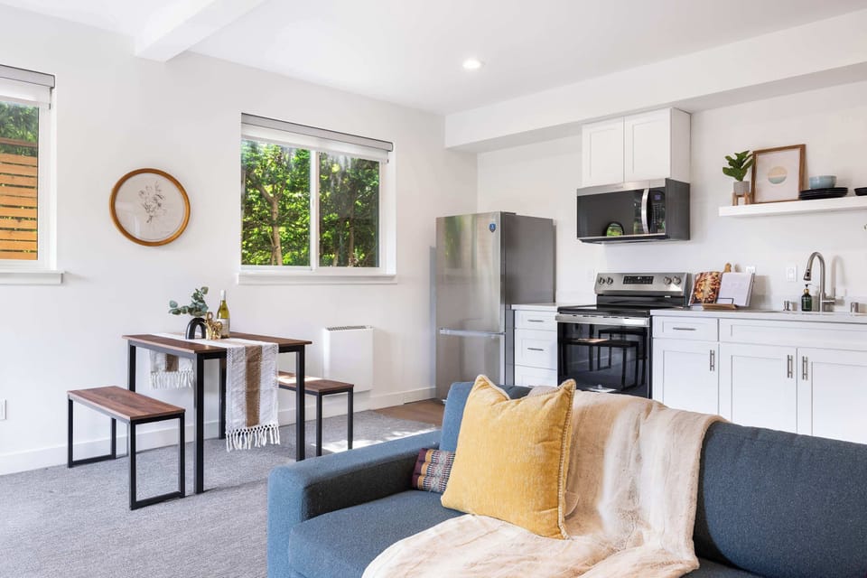 Bright open-plan living space with a blue sofa and kitchen.