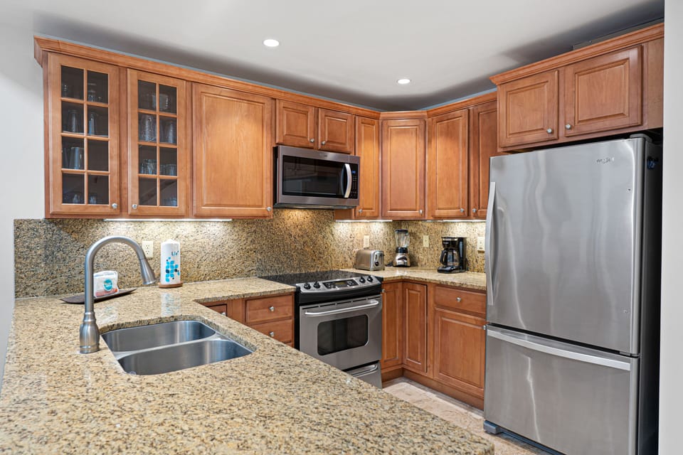 The updated kitchen is both functional and inviting, featuring granite countertops, warm wood cabinetry, and stainless steel appliances.