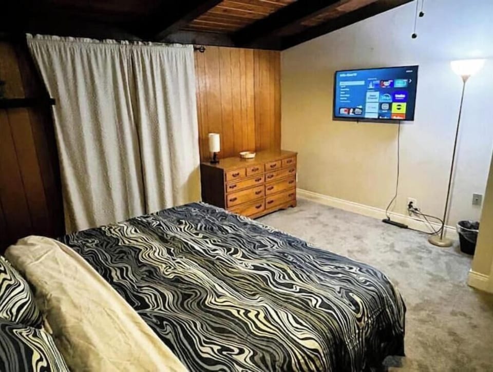Bright king bedroom with comfy bed, dresser, and TV.