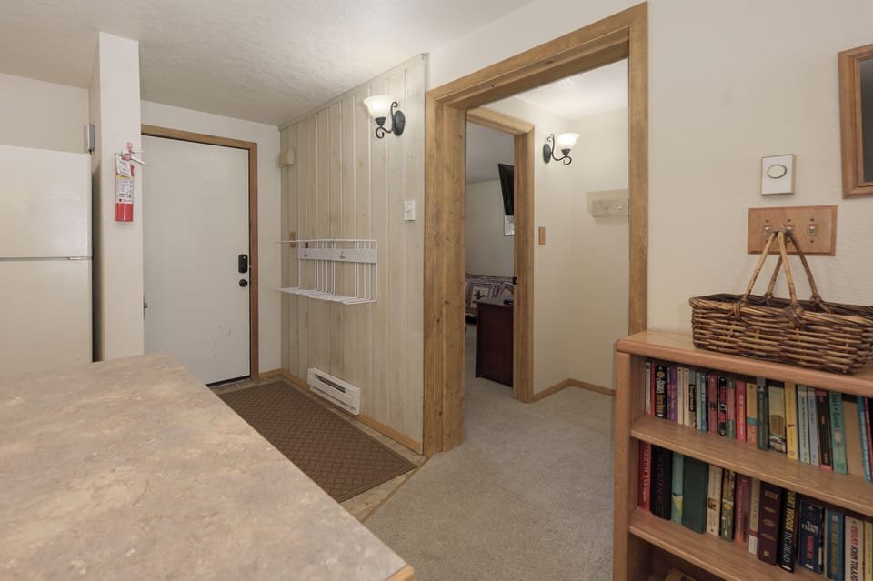 Step into your cozy entrance where warm wood accents and thoughtful touches like a mini-library create an inviting mountain retreat atmosphere.