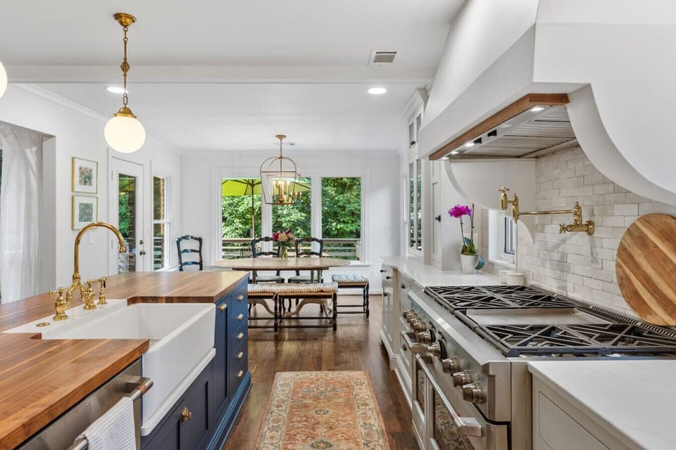 Recently updated state-of-the-art kitchen with a gas range, wall-mounted pot and kettle filler over the range, farm sink, and seating for four at the kitchen island.