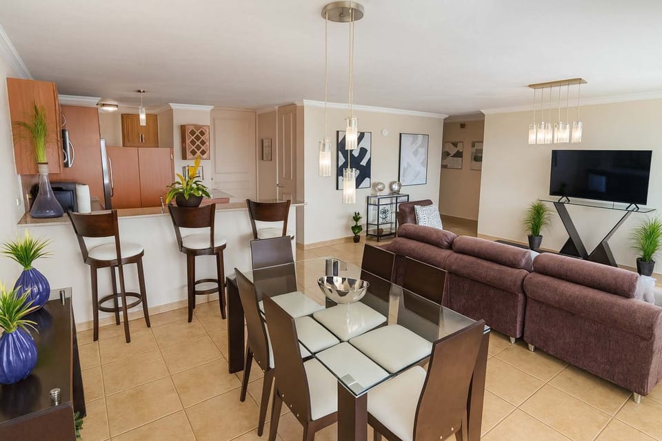 Spacious open-concept living area with elegant dining space, modern kitchen, and cozy lounge seating — ideal for relaxing or entertaining during your stay.